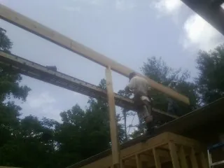 Carpenter setting a ridge beam over a new addition frame — Ice Dam Removal by Roofing Brothers in Tuttle