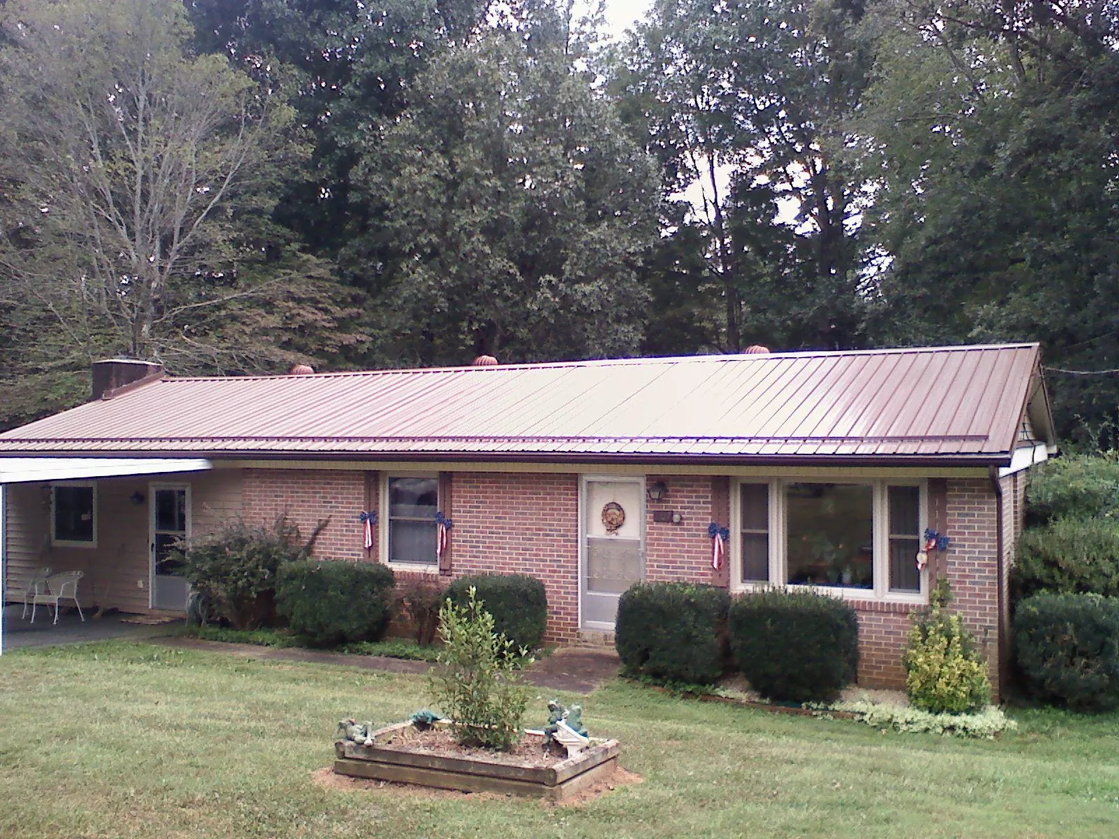 Bronze metal roof on a brick ranch home with a carport in Tuttle