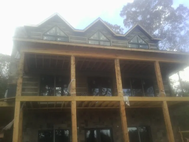Dormers and porch framing on a large log home under construction — Roof Coating work by our crew in Tuttle