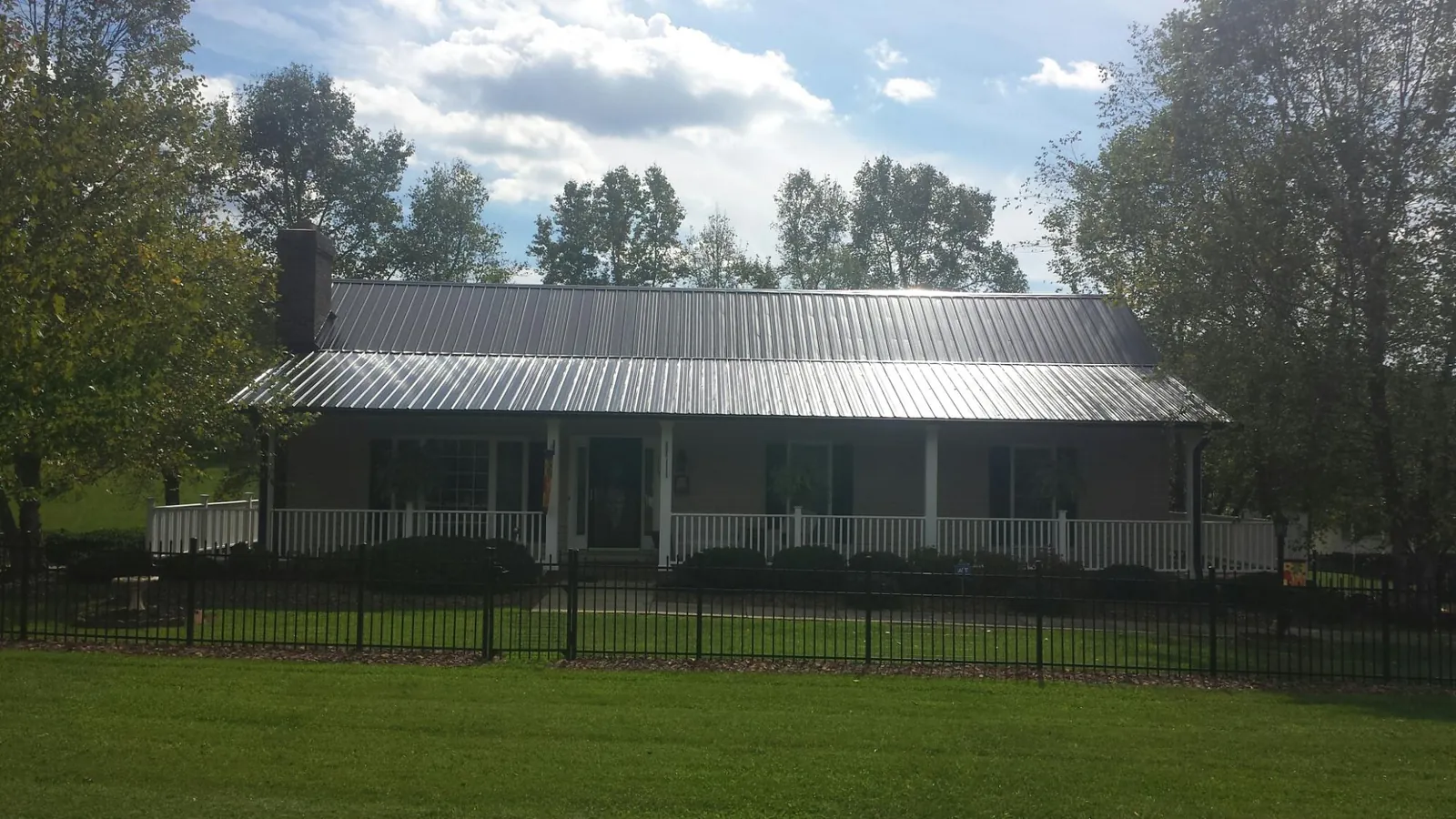 Gray metal roof on a brick ranch with a full width front porch — Gutter Guard Installation work by our crew in Tuttle